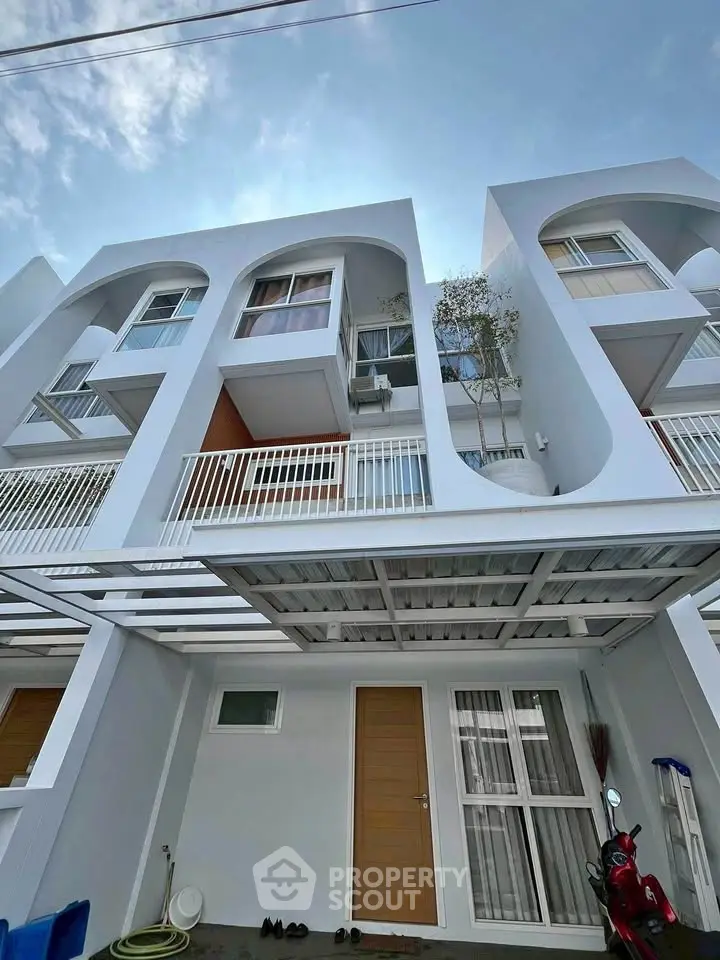 Modern three-story townhouse with sleek design and spacious balconies, perfect for urban living.