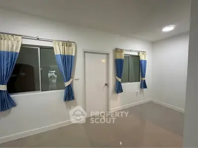 Spacious empty room with tiled floor and blue curtains, ideal for customization.