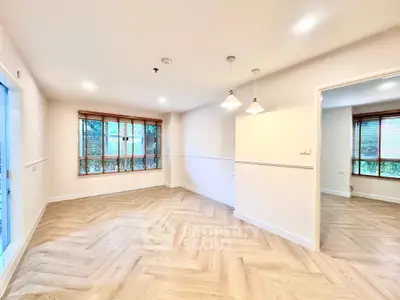 Spacious living room with herringbone flooring and large windows for natural light.