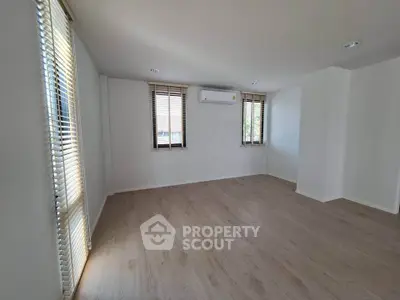 Spacious empty room with wooden flooring and large windows in modern apartment