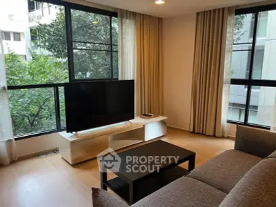 Spacious living room with large windows and modern furnishings in a city apartment.