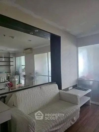 Cozy living room with modern decor and large mirror enhancing space.