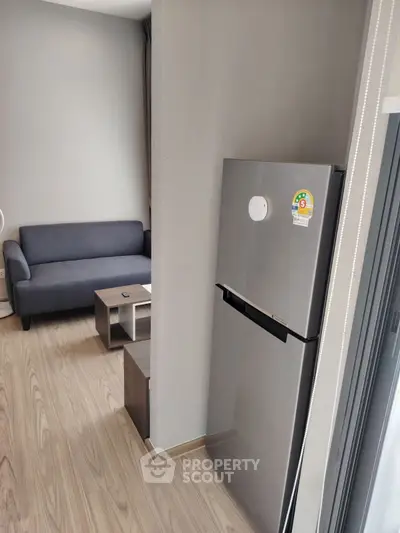 Modern apartment interior with sleek fridge and cozy living area