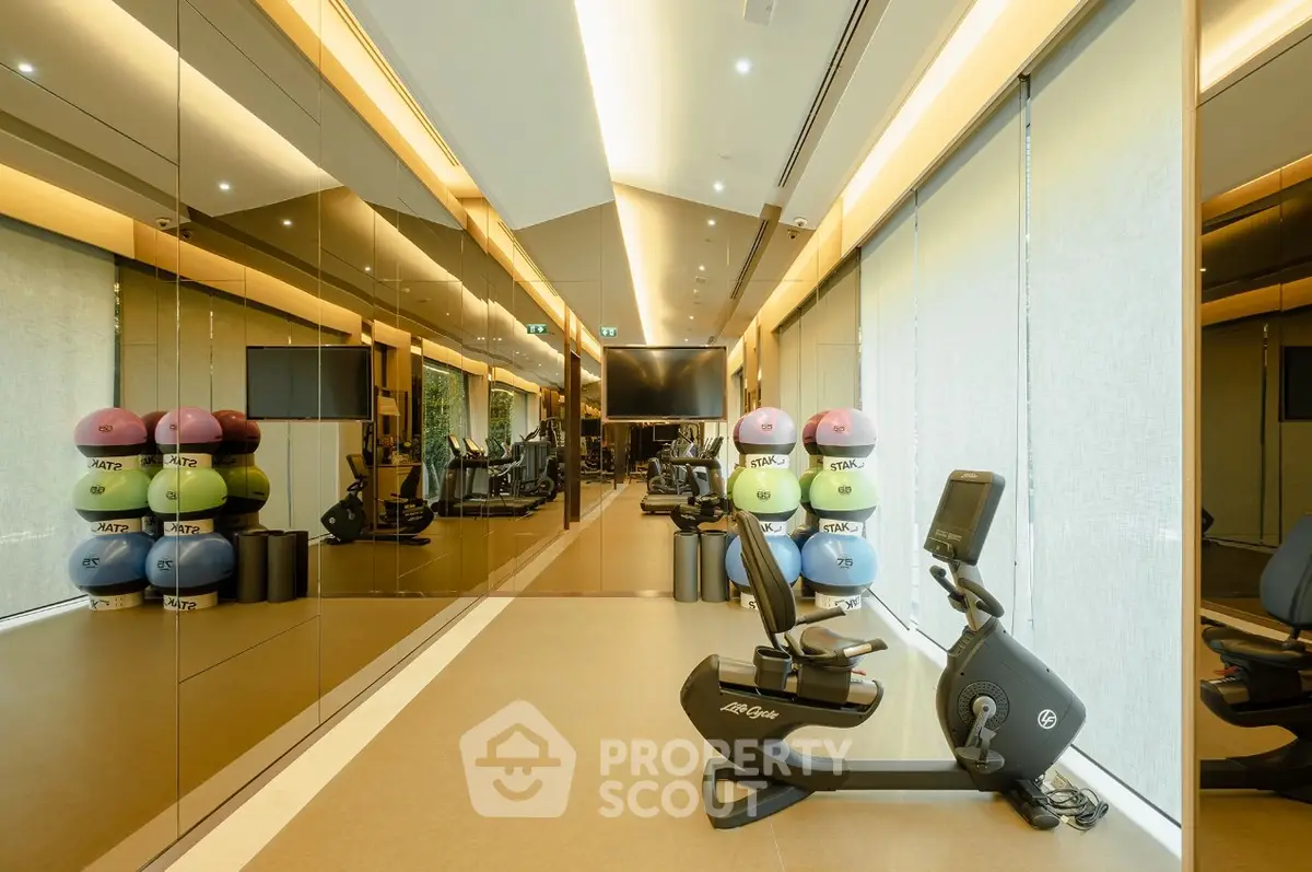 Luxurious gym with modern equipment and mirrored walls in upscale real estate property.