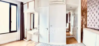 Spacious bedroom with modern decor and large window offering natural light.