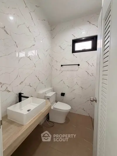 Modern bathroom with marble walls and sleek fixtures in a stylish home.