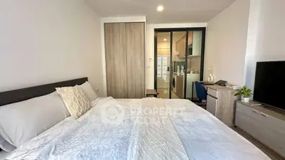 Modern bedroom with cozy bed, sliding closet, and view into a compact kitchen area.