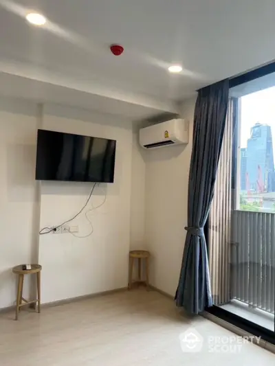 Modern living room with wall-mounted TV and city view balcony