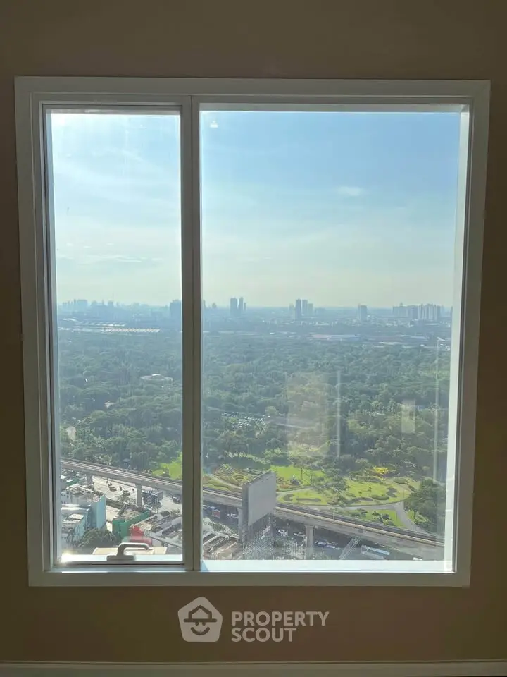 Stunning high-rise window view showcasing expansive cityscape and lush greenery.