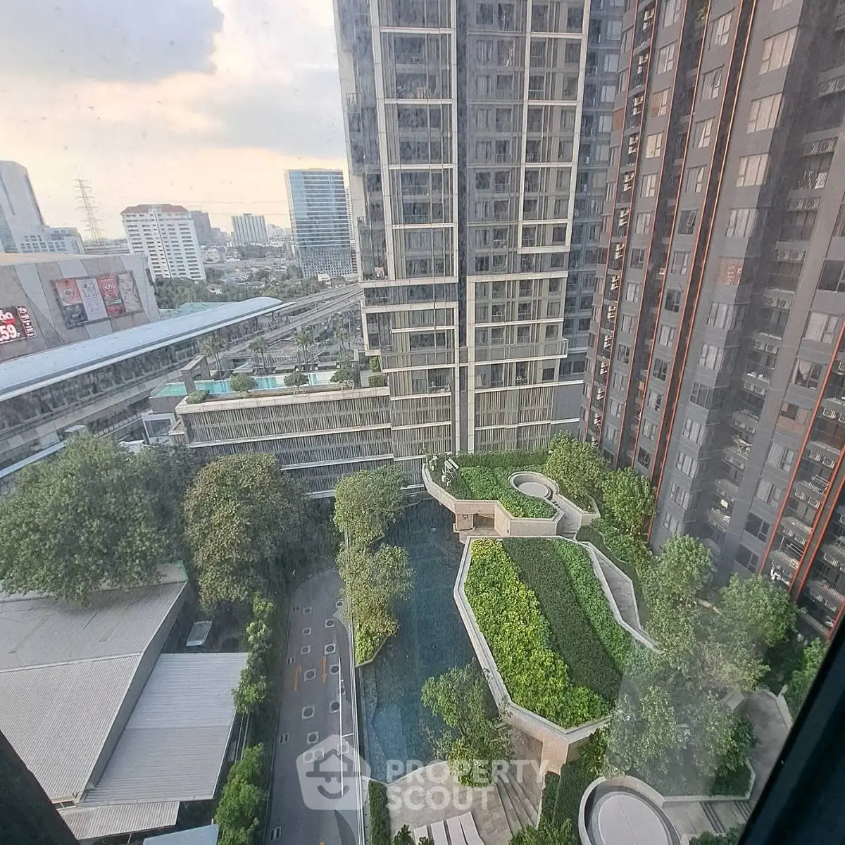 Stunning high-rise building with lush garden and pool view in urban setting.