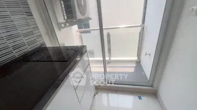 Compact kitchen with sleek design and balcony access, featuring modern appliances and bright natural light.