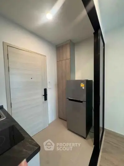 Modern kitchen with sleek fridge and minimalist design in compact apartment.
