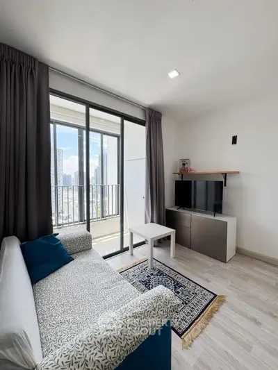 Modern living room with city view, stylish sofa, and entertainment center in a high-rise apartment.