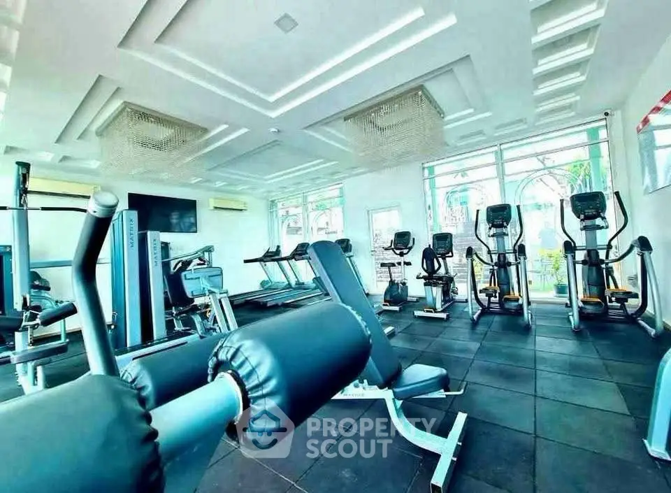 Spacious modern gym with state-of-the-art fitness equipment and large windows for natural light.