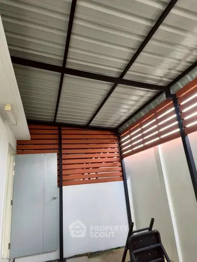 Modern covered outdoor area with metal roof and wooden slat walls, perfect for versatile use.