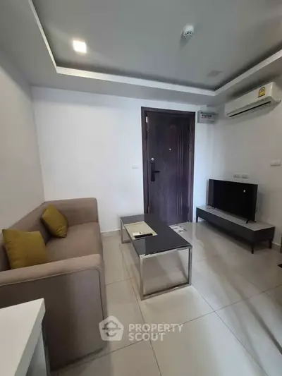 Modern living room with sleek furniture and air conditioning in a compact apartment.