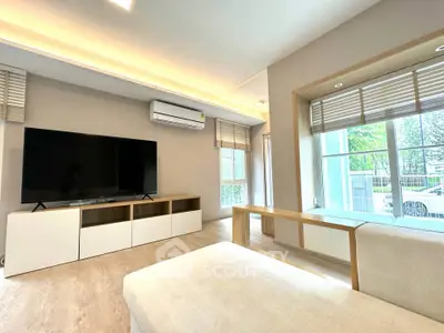 Spacious modern living room with large TV and natural light