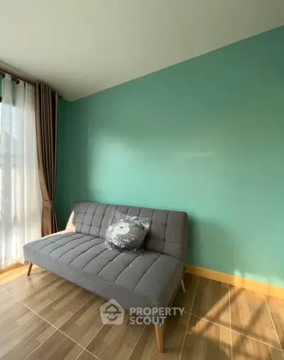 Cozy living room with stylish gray sofa and teal accent wall, perfect for relaxation.