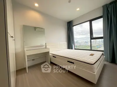 Modern bedroom with city view, featuring sleek furniture and large window.