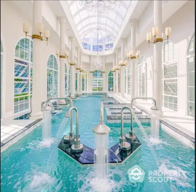 Luxurious indoor pool with elegant columns and skylight in a grand estate