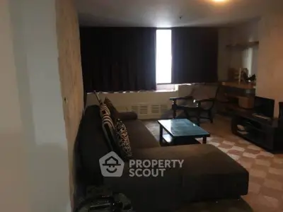 Cozy living room with dark sofa, coffee table, and entertainment unit, perfect for relaxation.