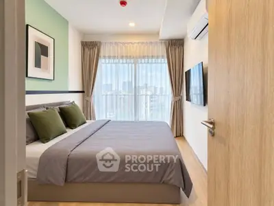 Modern bedroom with large window and stylish decor in urban apartment.