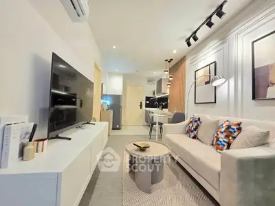 Modern living room with stylish decor and open layout, featuring a cozy sofa and large TV.