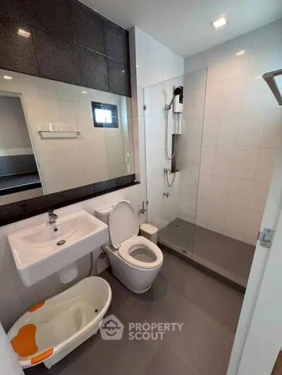 Modern bathroom with glass shower and sleek fixtures in contemporary home.