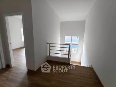Spacious hallway with wooden flooring and natural light, leading to multiple rooms.