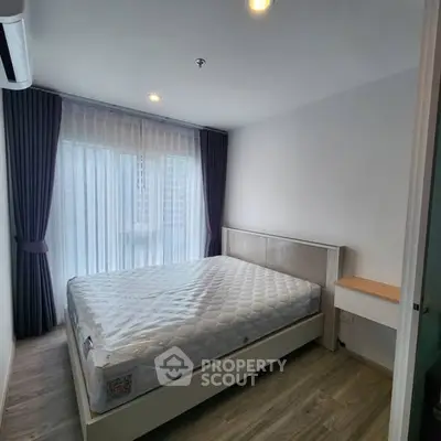 Modern bedroom with large window and elegant curtains, featuring a comfortable bed and stylish flooring.