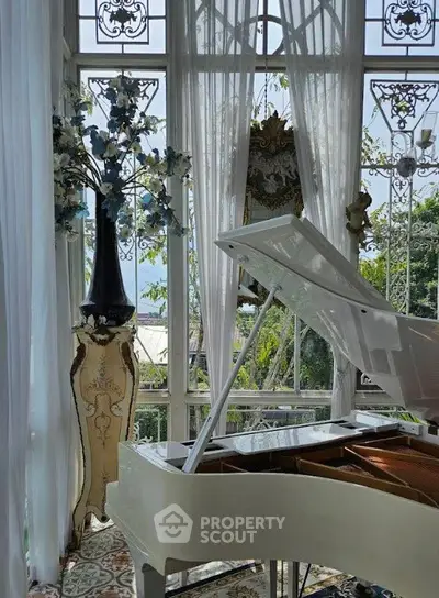 Luxurious living room with grand piano and elegant decor, featuring large windows and scenic garden view.