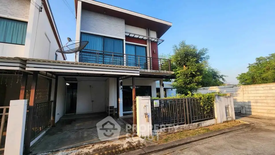Modern two-story house with balcony and driveway in a serene neighborhood.