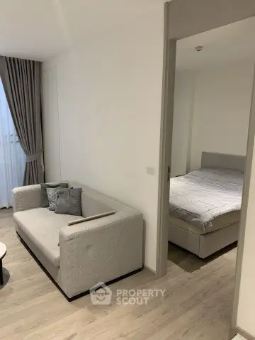 Modern apartment interior with cozy living room and adjacent bedroom, featuring stylish decor and natural light.