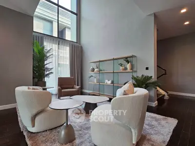 Luxurious modern living room with high ceilings, elegant furniture, and large windows for natural light.