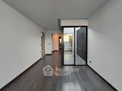 Spacious modern living room with sleek wooden flooring and large glass doors.