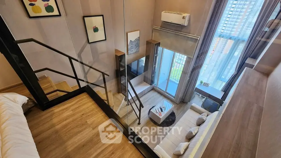 Modern loft apartment with stylish living room and large windows offering natural light and city views.