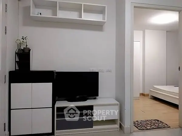 Modern apartment interior with sleek TV unit and cozy bedroom view.