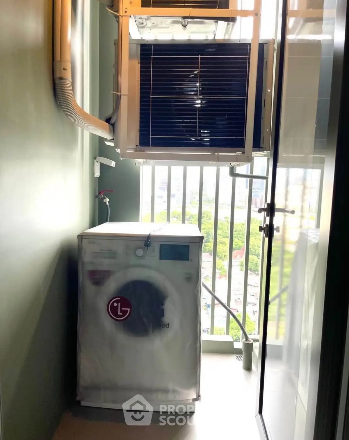 Compact laundry area with washing machine and city view from balcony.