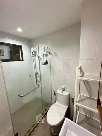 Modern bathroom with glass shower enclosure and sleek fixtures in a contemporary apartment.