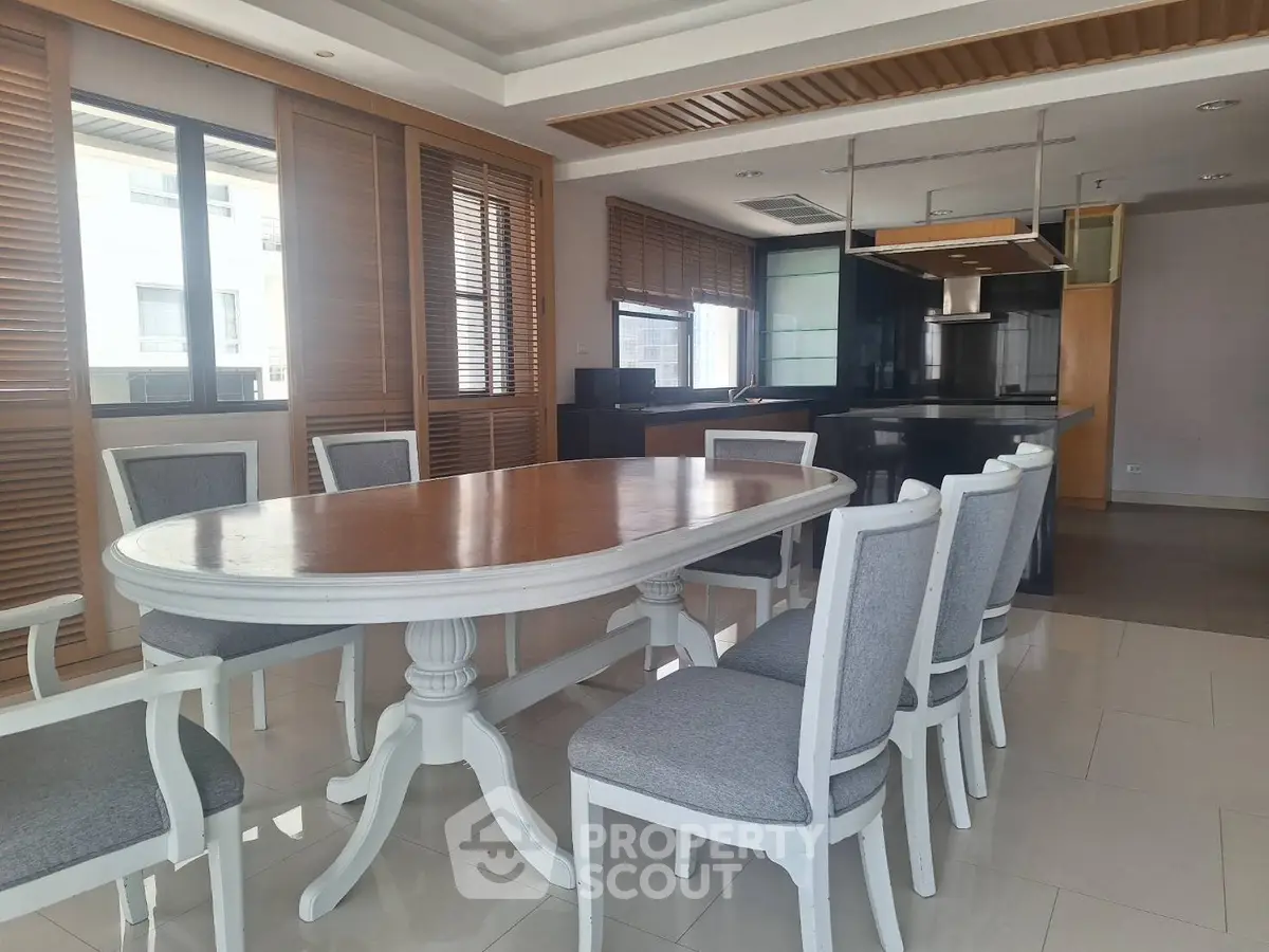 Spacious dining area with elegant table and chairs, featuring modern kitchen with sleek design.