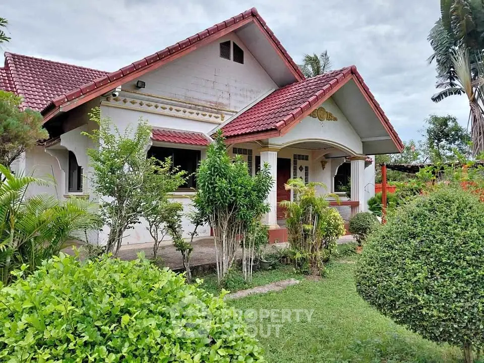 Charming single-story house with red roof and lush garden, perfect for serene living.