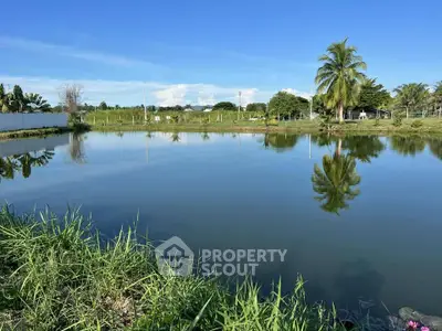 Scenic view of tranquil pond with lush greenery and clear blue sky, perfect for serene living.