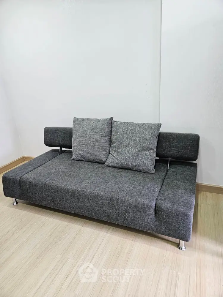 Modern gray sofa in minimalist living room with wooden flooring