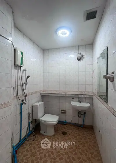 Spacious bathroom with modern fixtures and tiled walls, featuring a shower and toilet.