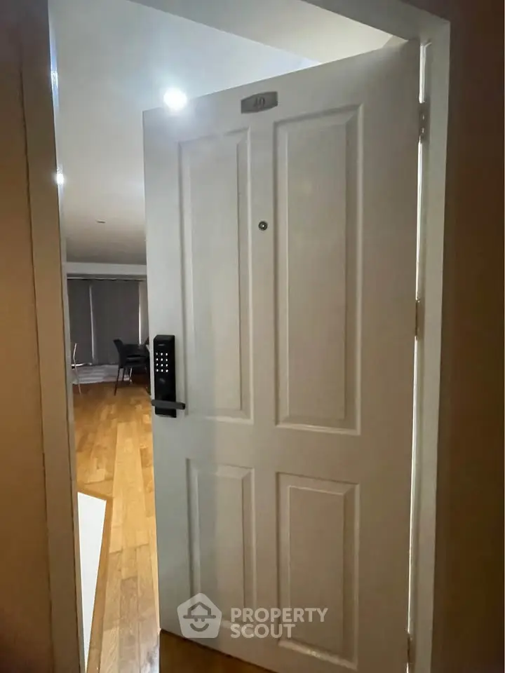 Modern apartment entrance with electronic lock and wooden flooring.