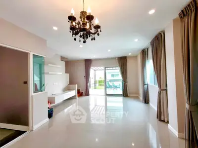 Spacious modern living room with elegant chandelier and large windows for natural light.