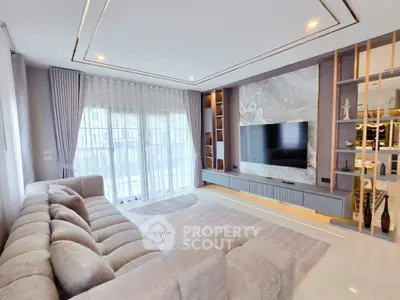 Luxurious modern living room with plush sofa and large TV, perfect for relaxation and entertainment.