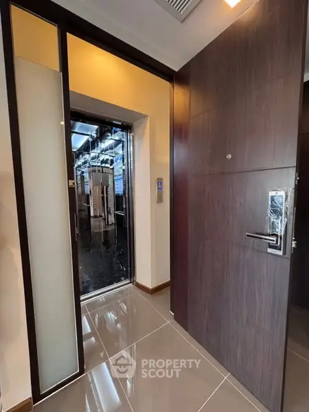 Modern apartment entrance with sleek elevator access and stylish wooden door.