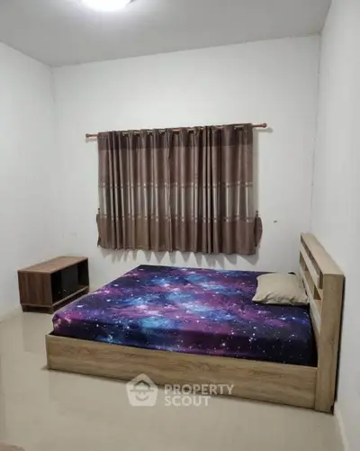 Cozy bedroom with galaxy-themed bedding and minimalist wooden furniture.