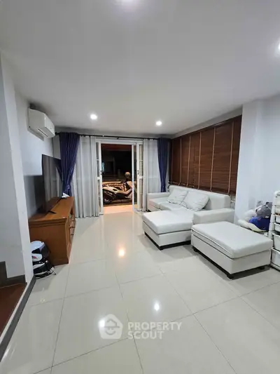 Spacious modern living room with sleek white furniture and large windows for natural light.